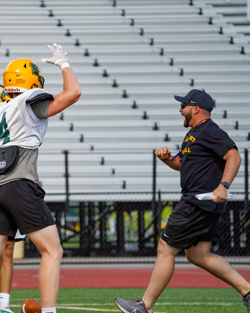 Coach Michael Peters celebrating with a receiver at SUNY Brockport